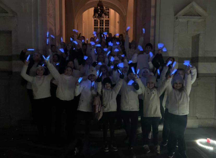 Barn i vita tröjor viftar med lysande blå fjädrar